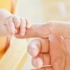 csecsemő megfogja egy felnőtt ujját (fénykép)